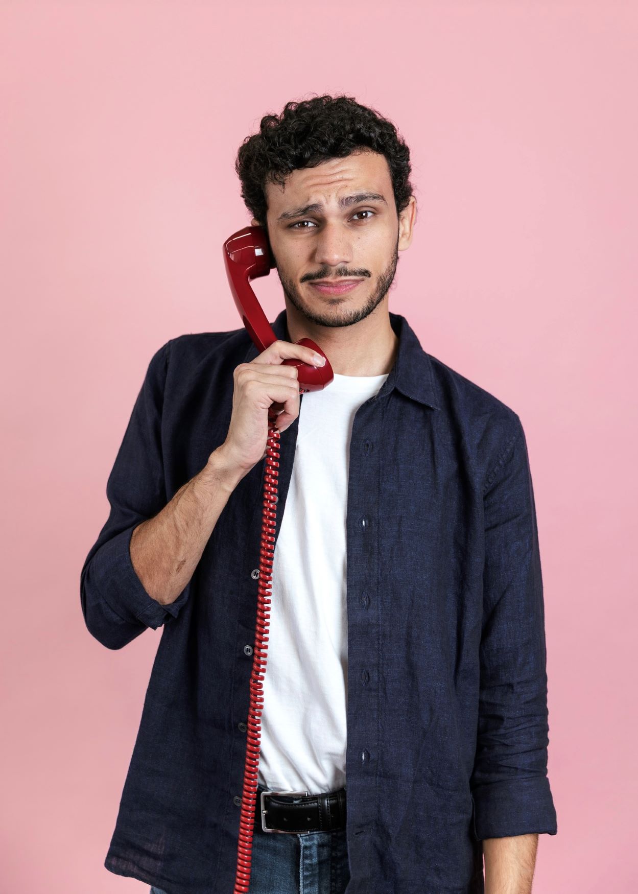 Bryan looking confused using a red corded phone